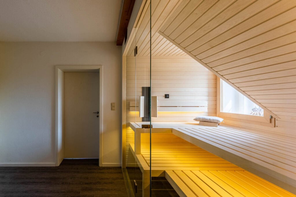 Glasfront der Dachschrägen-Sauna, rechts folgt die Verkleidung dem Dach