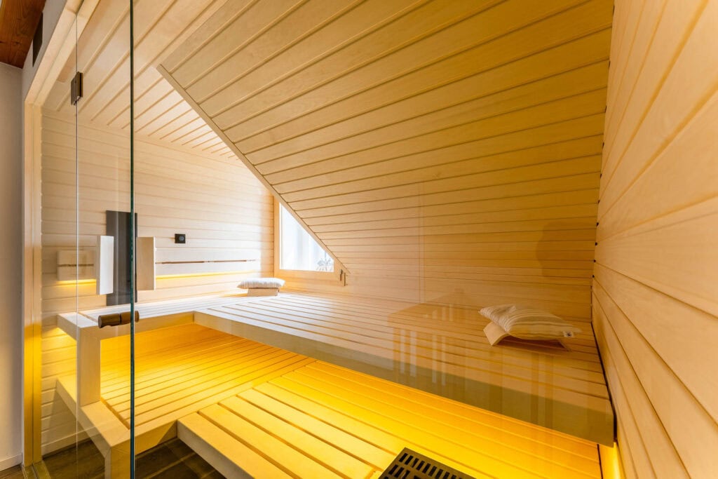 Innenraum der Dachschrägen-Sauna mit indirekter Beleuchtung unter den Bänken